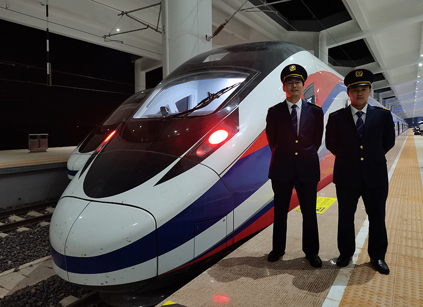 劉銀能（右一）與中國師父鄔俊鴻在動車組前合影。受訪者供圖
